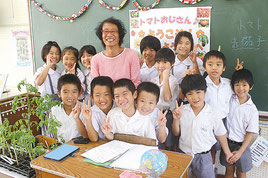 本村シュウさんが海星小2年生児童にミニトマトの苗などを贈呈した=17日午前、海星小学校