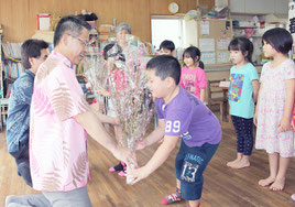 桃の花を贈る名渡山秋彦支社長=27日午後、ひまわり保育園