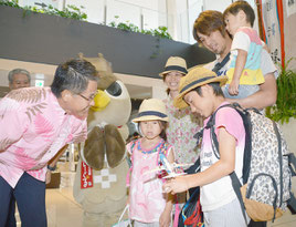 レセプションで歓迎された坂本さん家族。琉駕君(右手前)は飛行機の模型を受け取り、「飾って遊ぶ」とはしゃいだ=1日、石垣空港