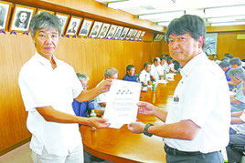 要請書を手渡す柳澤正和野底小PTA会長(左)と金城弘一石垣市総務部長(右)=28日午後、石垣市役所