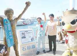 記念パネルの脇で記念写真に収まる具志堅さん(左)と中山市長=離島ターミナル