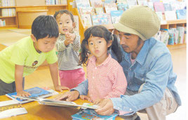 市立図書館で読書を楽しむ親子(資料写真)。北西部地区の住民は近隣校でも図書を返却できるようになる。