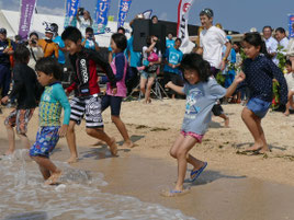テープカット後、子どもたちが一斉に海へと駆けだした=18日午前、小浜島はいむるぶしビーチ