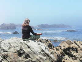 sentada na rocha frente ao mar a meditar