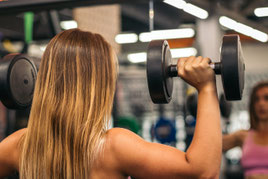 Frau trainiert an einem Fitnessgerät zur Erhaltung von Muskelmasse und körperlicher Belastbarkeit.