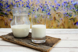 Glaskrug Glas Milch Blumen Holzbrett