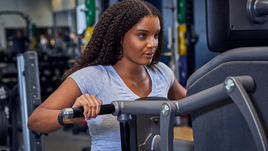 Frau trainiert an einem EGYM Gerät für den Rücken im Fitnessstudio mit KI-gesteuertem Trainingsplan