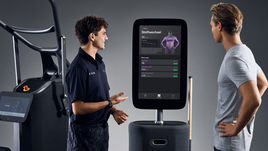 Trainer erklärt einem Mitglied die Körperanalyse am EGYM Fitness Hub mit digitalen Messwerten zu Körperfett, BMI und Stoffwechsel