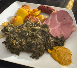 weisser eckiger Teller mit einer Portion gekochten Grünkohl, Kassler, Wurst, Bratkartoffeln und Heimat-Senf