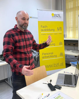 Fachtrainer erklärt das Ausbildungskonzept vor dem gelben Rollup des Bildungszentrums Lenzing