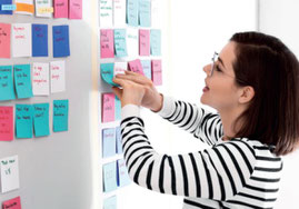Eine Frau klebt Post-Its an ein Whiteboardd