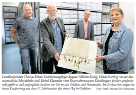 Vier Personen präsentieren eine alte Urkunde im Archivmagazin