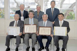 文化財指定書などを手に記念撮影する豊川敏彦さん(前列左から3番目)ら=今年1月10日、市教委