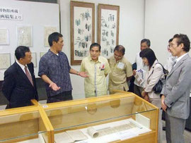 写真 高良館長(左から2人目)から展示している古文書の説明をうける関係者ら=22日午前、市立図書館