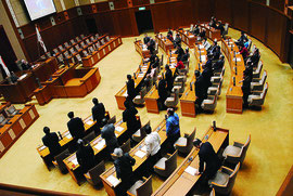百条員設置に賛成して起立する自民党議員(手前)。与党の反対多数で否決された=29日午後、県議会