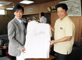 サイン入りTシャツをプレゼントした新城選手(左)=29日午前、市役所