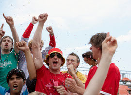 A group of spectators with arms lifted in jubilation