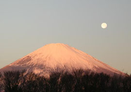 朝焼けに染まる富士山と満月が並ぶ写真