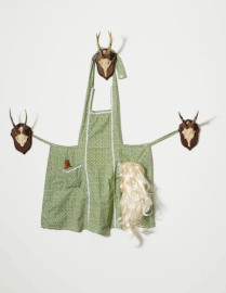 Behind the glory hole, 2026 / Küchenschürze, Perücke, Objekt, 3 Geweihe / ca. 162 x158 x22 cm