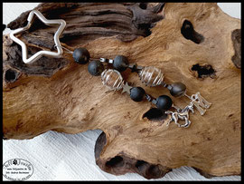 Bild 46: Eingefasste Pferdehaare in eine Glasperle und von einem silbernen Perlenkäfig umrandet. Verarbeitet sind marmorierte Perlen und Hämatitsternchen. Als Hingucker dienen zum Abschluss ein Pferdeanhänger und ein Buchstabenanhänger . Preis: 40 Euro