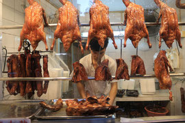Canard laqué. A Pékin, le canard laqué est le passage obligé ! Accrochés dans les vitrines, il faut les laisser « mariner » quelques jours. En bas, disposées dans un plat, ce sont les têtes. Bon appétit !