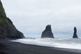 Reynisfjara, beim südlichsten Punkt von Island (Kap Dyrhólaey), mit schwarzem Lavastrand und Basaltsäulen. Die schwarzen Felsnadeln ('Reynisdrangar, 'Skessudrangur', 'Landdrangur' und 'Langsamur') sind drei Trolle, die ein Schiff ans Land bringen wollten 