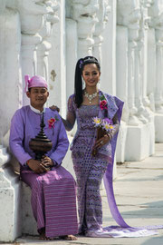 Hochzeitspaar in Myanmar: Die Braut in Longgyi und Schärpe, der Bräutigam mit traditionellem Anzug inkl. Gaung-Baung (Kopfbedeckung).  Die Festlichkeiten einer Hochzeit ähneln sehr stark den in Europa üblichen Bräuchen.