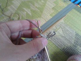 2.左の棒針の下から、人差し指に掛けた糸を絡めとります。