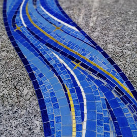 Zoom sur une rivière en mosaïque d' émaux bleus et d'or, incrustée dans un monument funéraire en granit  tarn gris.