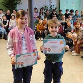 Ein Mädchen und ein Junge halten ihre Urkunde als Sieger in der Hand