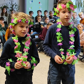 Zwei Jungen aus der Löwenklasse stehen mit Blumenkränzen geschmückt nebeneinander