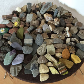 "SteinGarten" (2016), 1 m Durchmesser; Raumobjekt mit Steinen auf rundem Tisch (Tisch gefertigt von Günther J. Schaefer); Steine in verschiedenen alten Techniken ummantelt; Schafwolle, Alpaka, Mohair, Hundehaare, z.T. selbstgesponnen, z.T. pflanzengefärbt