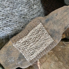 Detail von "SteinGarten" (2016), Raumobjekt mit Steinen; Steine z.T. umstrickt, umhäkelt, umwebt, umfilzt, umnadelt (Nadelbindung), z.T. mit Stickerei und der Technik des Einhängenden Verschlingens; Schafwolle, Alpaka, Mohair, z.T. pflanzengefärbt (Schwar