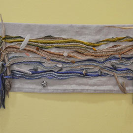 "Spülsaum" (2015), 68  x 30 cm, Wandobjekt in Fingerwebtechnik; Wolle, Baumwolle, Leinen und Seide; Strandgut (Muscheln, Haifischzahn, Feder, Feuerstein, Bernsteine, Schwemmhölzer)