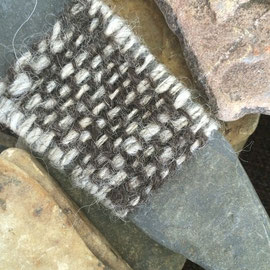 Detail von "SteinGarten" (2016), Raumobjekt mit Steinen; Steine z.T. umstrickt, umhäkelt, umwebt, umfilzt, umnadelt (Nadelbindung), z.T. mit Stickerei und der Technik des Einhängenden Verschlingens; Schafwolle, Alpaka, Mohair, z.T. pflanzengefärbt (Schwar