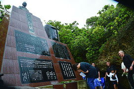 忘勿石之碑前で慰霊祭が執り行われた=15日、南風見田浜