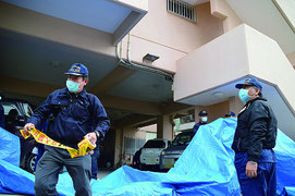 容疑者宅でブルーシートと規制線を張る捜査員=11日午後、登野城(画像は一部加工しています)