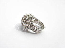 Une bague boule en argent ajourée est vue de profil.