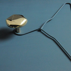 zoom sur le bouton de la patère ronde en laiton doré avec une surface facettée et un effet miroir