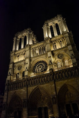 Notre Dame bei Nacht kannst du u. a. im Rahmen einer Seinerundfahrt betrachten. Vor dem Kirchenportal tummeln sich allerhand Gaukler, Künstler und Maler