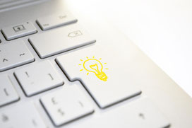 Hell leuchtende Glühbirne auf einer Computer-Tastatur.