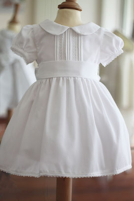 Robe cérémonie fille en piqué de coton blanc et dentelle de coton avec une ceinture rose. Modèle de robe Inès créé par Fil de Légende. Magasin vêtements cérémonie enfants Paris, Neuilly-sur-Seine. Expéditions en France et à l'International.