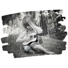 Ein Kind spielt eine Akustikgitarre im Freien, umgeben von Natur