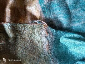 détail d'un poncho fait de laine merinos, chameau, alpaga et soie, feutrés sur de la gaze de soie de marguilan. tons turquoise et moutarde