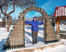 Anna Zīle standing with an arch made from empty bottles on a winter day in Litene, Latvia