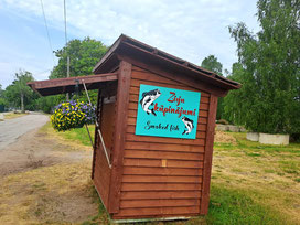 Brown timber fish stand with blue sign in Kolka, Latvia