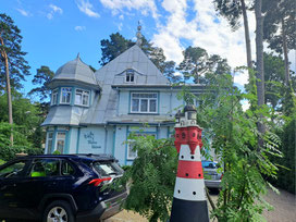 Historic timber house with two metre tall model of a lighthouse in front in Jurmala, Latvia