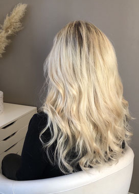 Cette photo représente une femme blonde de dos qui vient de recevoir un pose d'extensions de cheveux naturelles blondes.