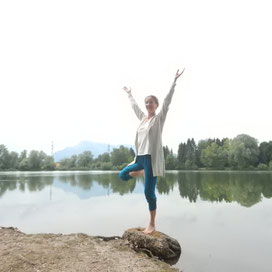 Frau steht auf einem Stein am See