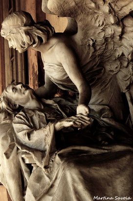 Cimitero di Verona. Un bellissimo angelo accompagna l'anima dell'anziana donna morente, prendendola teneramente per la mano e sollevandola dal suo giaciglio. 
